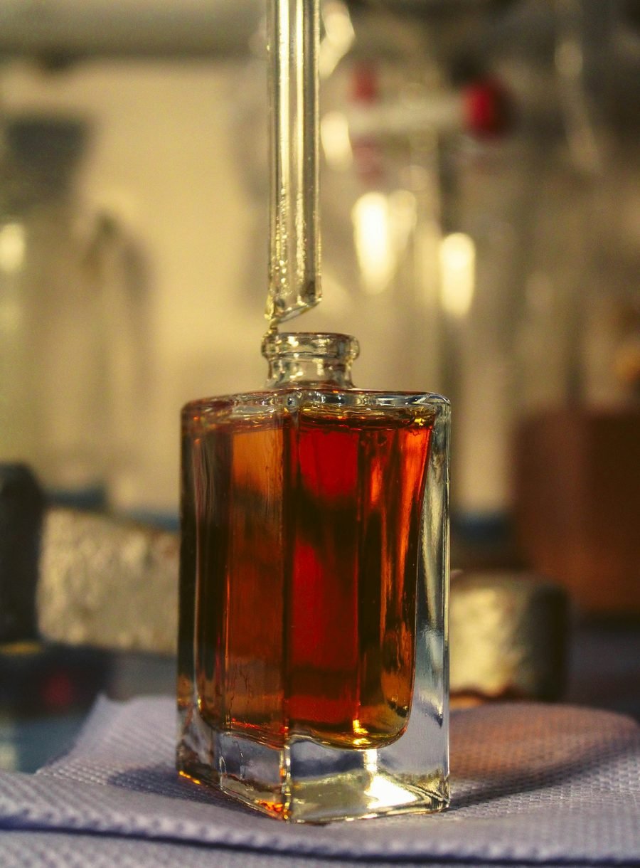 Fragrance being dispensed into a glass bottle